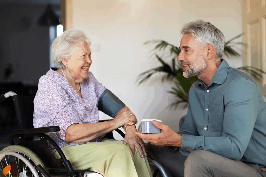 Angehöriger unterstützt ältere Frau im Rollstuhl und erklärt Pflegeleistungen.