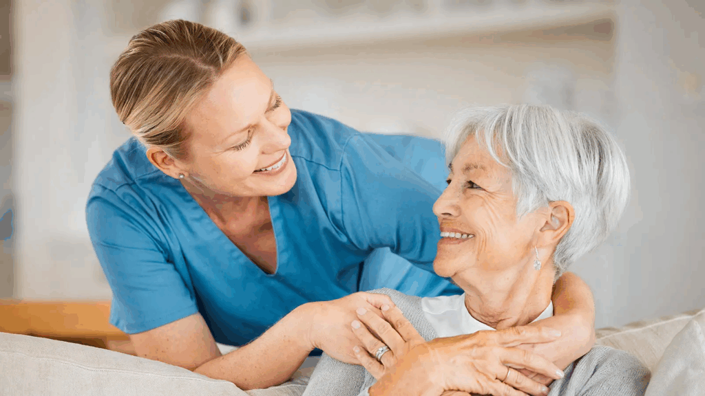 Pflegekraft zeigt Zuwendung und Unterstützung für ältere Frau im häuslichen Umfeld.