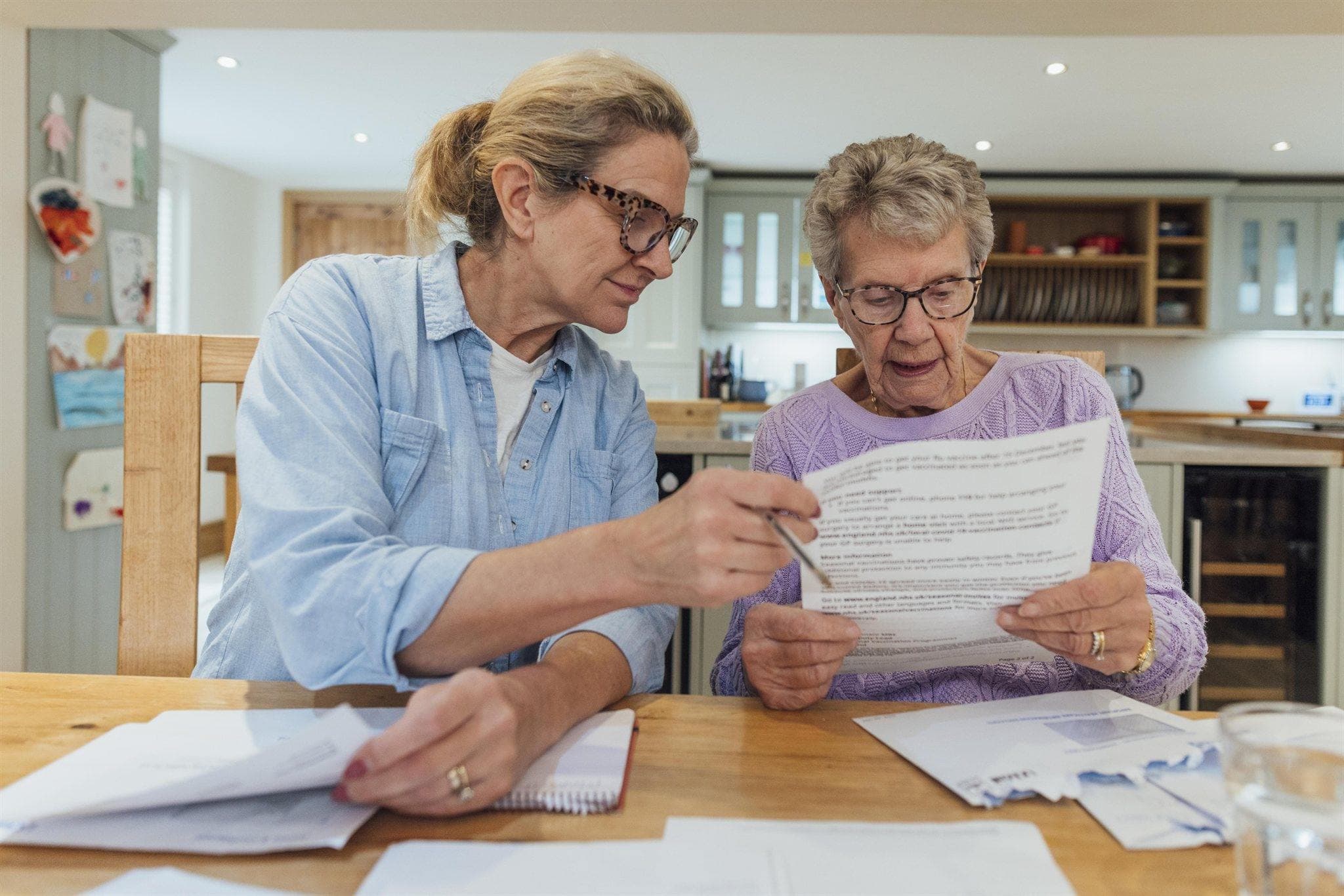 Tochter und ältere Mutter prüfen gemeinsam am Küchentisch einen Bescheid – die Pflegereform 2026 trifft Familien, wenn sie den Pflegefall organisieren müssen