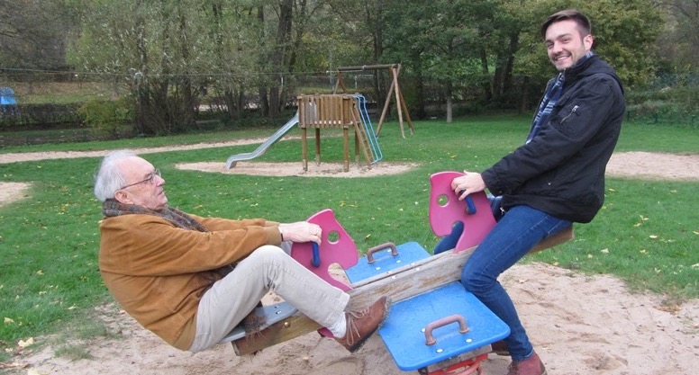 Großvater und Enkel lachen zusammen auf einer Wippe